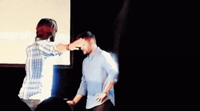 Man Pointing At Another Man's Head In Front Of Screen GIF