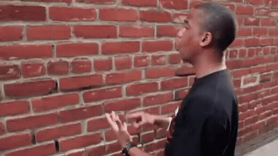 Man Pointing At Red Brick Wall GIF