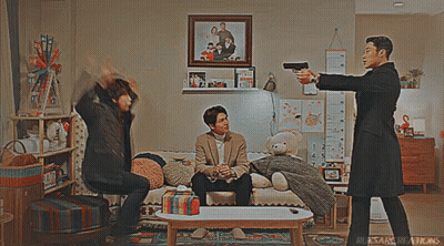 Man Pointing Gun At Another Man On Couch GIF