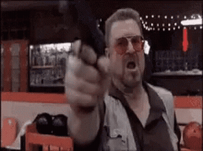 Man Pointing Gun At Camera In Bowling Alley GIF