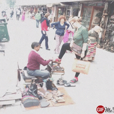 Man Polishing Woman's Shoe On Sidewalk GIF