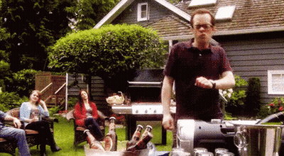 Man Pouring Beer Into Bucket While People Sit on Lawn