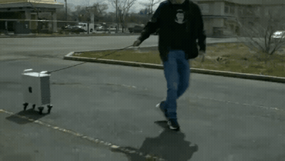 Man Pulling Small Box On A Leash GIF