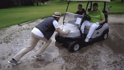 Man Pushing Golf Cart Through Muddy Field GIF