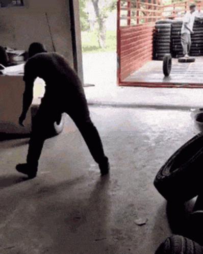 Man Pushing Tire In Garage GIF