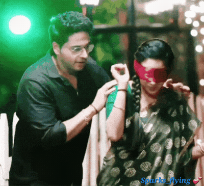 Man Putting Red Blindfold On Woman With Sparks Flying GIF