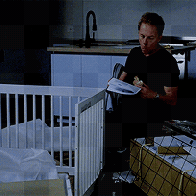 Man Reading Book in Front of Baby Crib