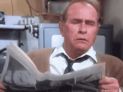 Man Reading Newspaper With Eyes Closed