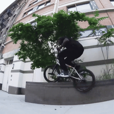 Man Riding Bike In Front Of Building With N.Y.C. Sign GIF