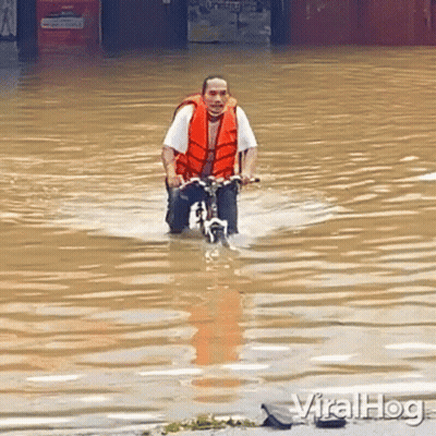 Man Riding Bike Through Flooded Street GIF