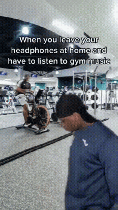 Man Riding Exercise Bike With Headphones GIF