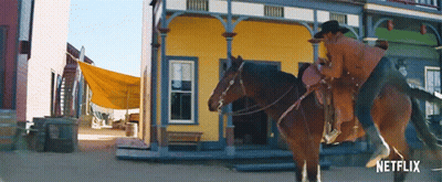 Man Riding Horse In Front Of Yellow Netflix Building GIF