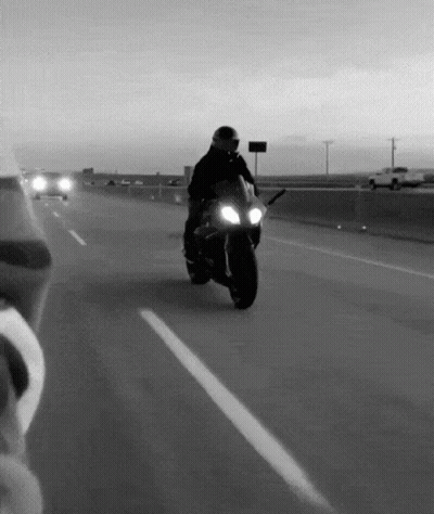 Man Riding Motorcycle Down Highway Black And White GIF