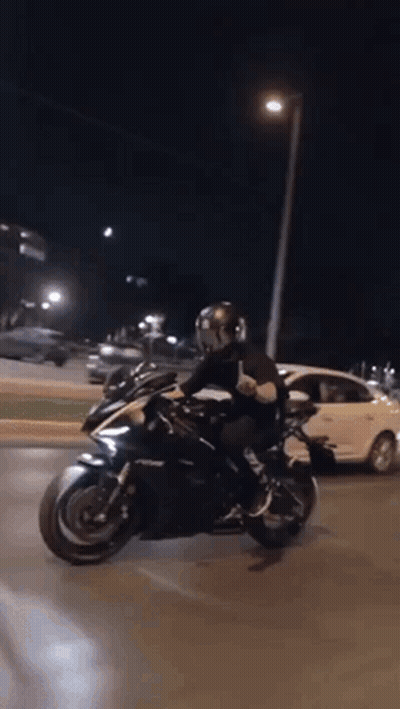 Man Riding Motorcycle Down Street At Night GIF