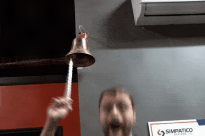 Man Ringing Bell In Front Of Simpatico Systems LLC Sign GIF