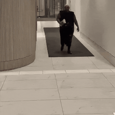 Man Running Down Hallway With Water Bottle
