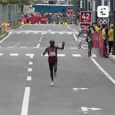 Man Running Down Street With 42 Km Sign GIF