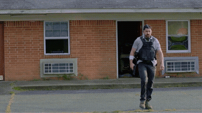 Man Running In Front Of Brick Building With Explosion GIF