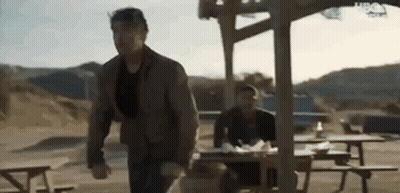 Man Running Towards Picnic Table While Another Man Sits GIF