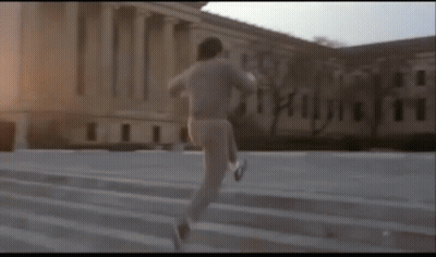 Man Running Up Stairs In Front Of Large Building GIF