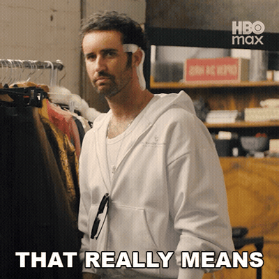 Man Saying That Really Means In Front Of Clothes Rack GIF