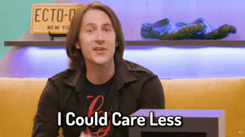 Man Says I Could Care Less In Front Of Yellow Couch GIF