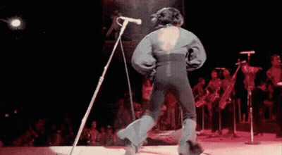Man Singing Into Microphone And Dancing On Stage GIF