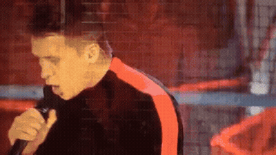 Man Singing Into Microphone In Black And Red Jacket GIF