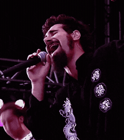 Man Singing Into Microphone In Black Shirt With Chinese Symbols GIF