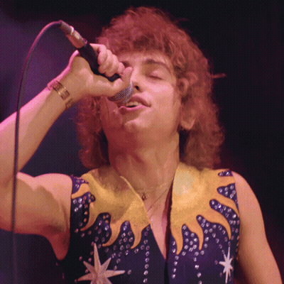 Man Singing Into Microphone In Blue And Yellow Outfit GIF