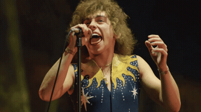 Man Singing Into Microphone In Blue And Yellow Outfit GIF