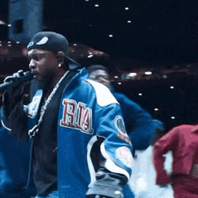 Man Singing Into Microphone In Blue Ria Jacket GIF