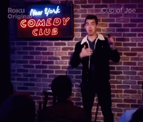 Man Singing Into Microphone In Front Of Comedy Club Sign GIF