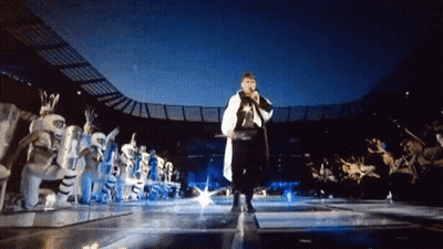 Man Singing Into Microphone In Front Of Crowd GIF