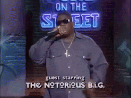 Man Singing Into Microphone In Front Of On The Street Sign GIF