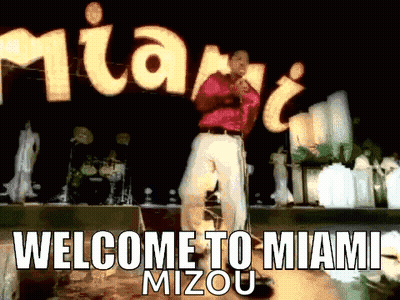 Man Singing Into Microphone In Front Of Welcome To Miami Sign GIF