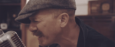 Man Singing Into Microphone In Hat And Black Jacket GIF