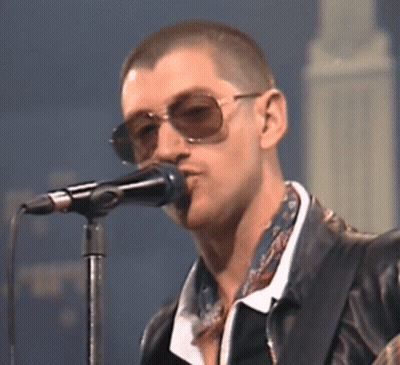 Man Singing Into Microphone in Sunglasses and Leather Jacket