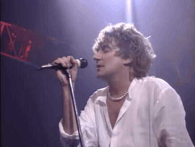Man Singing Into Microphone On Stage In Dark Room GIF