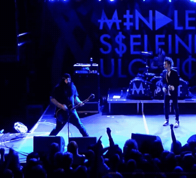 Man Singing Into Microphone On Stage With Selfie Sign GIF