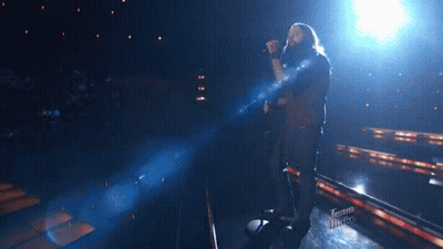 Man Singing Into Microphone On Stage With Team Voice Logo GIF