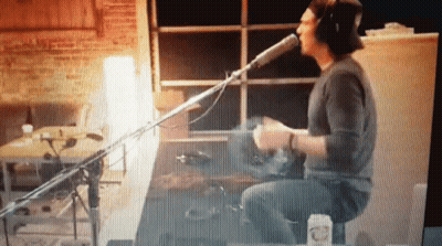 Man Singing Into Microphone Playing Drums GIF