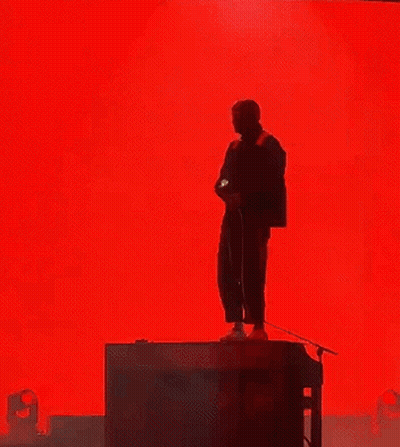 Man Singing Into Microphone Red Backdrop GIF