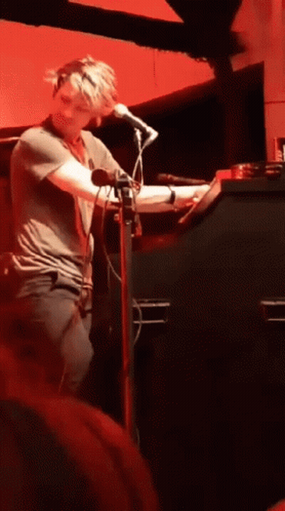 Man Singing Into Microphone Red Wall GIF