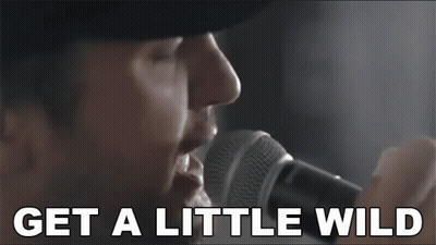 Man Singing Into Microphone Saying Get A Little Wild GIF