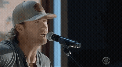 Man Singing Into Microphone Wearing Baseball Cap GIF
