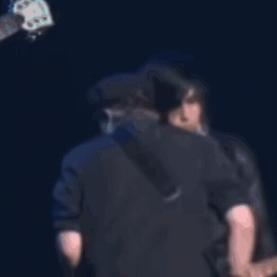 Man Singing Into Microphone While Another Kisses His Cheek GIF