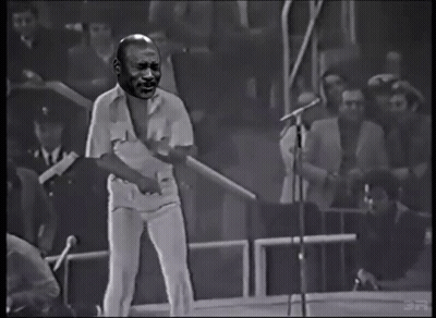 Man Singing Into Microphone With Crowd Behind GIF
