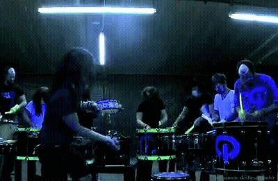 Man Singing Into Microphone With Drummers GIF