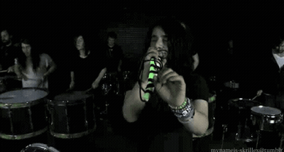 Man Singing Into Microphone With Drummers GIF